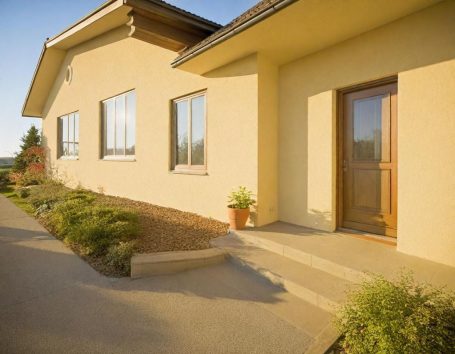 Modernes Haus Helles Gebäude mit einer Veranda und einem Eingang, umgeben von Gartenanlagen.